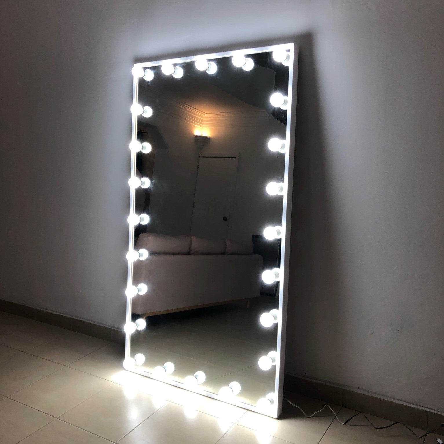 Espejo hollywood; Espejo de gran tamaño recargado sobre una pared, la orilla del espejo cuenta con varios focos instalados en la orilla, que se prenden y otorgan luz.
