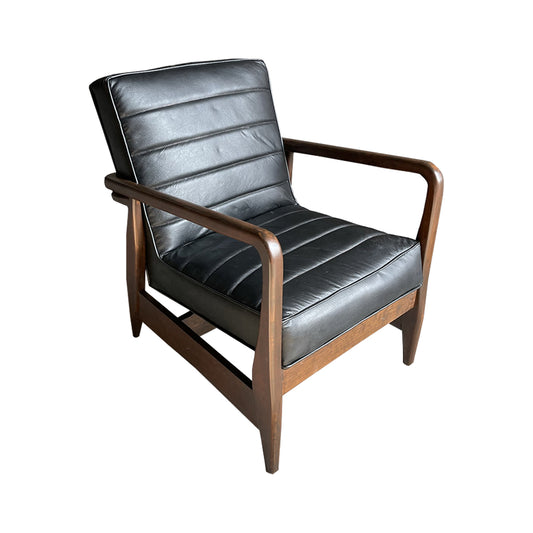 Sillón Dover, con respaldo y asiento acolchonados, forrada de piel y con estructura de madera en tono natural.